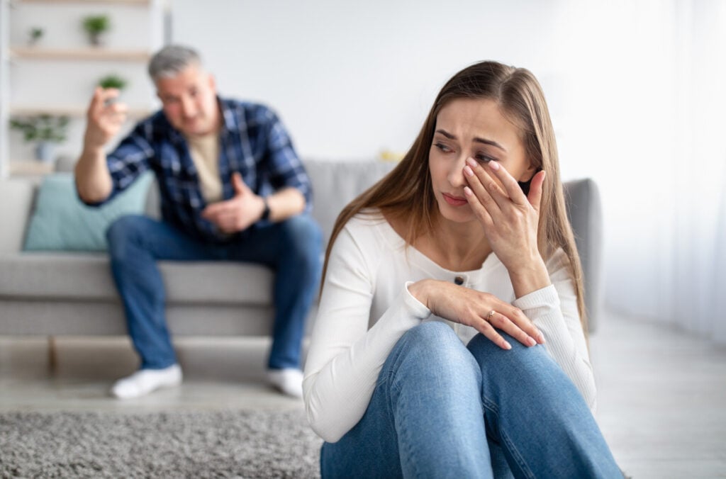 Am I Narcissistic or the Victim? 1 A woman sat on the floor crying while a man behind her is shouting at her